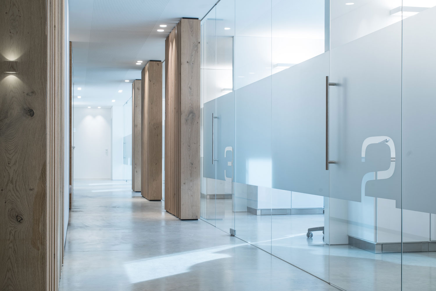 Discreet downlights, flush-mounted in the ceiling, provide uniform illumination in the hallway of a doctor's office.