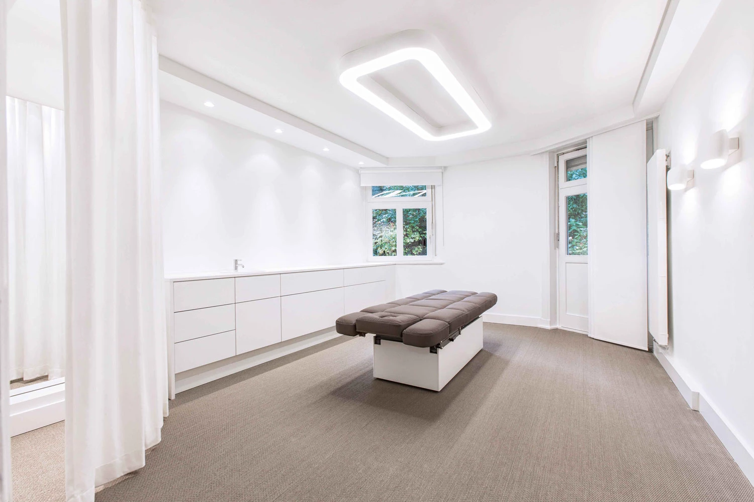 A rectangular surface-mounted ceiling luminaire provides a calm and relaxing lighting mood in the treatment room for massages.